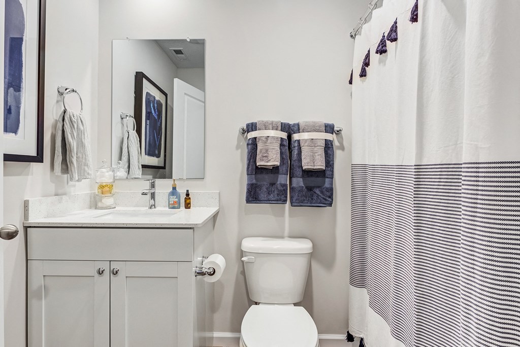 a white bathroom with a white toilet and a sink and a striped shower curtain