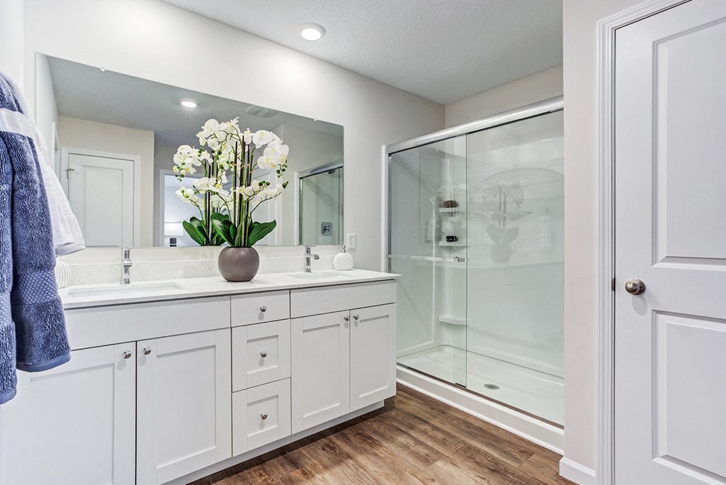 a white bathroom with a large mirror and a shower