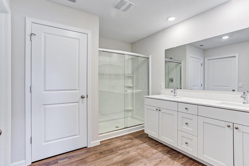 a bathroom with white cabinets and a glass shower