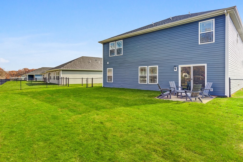 a blue house with a yard and a patio with chairs