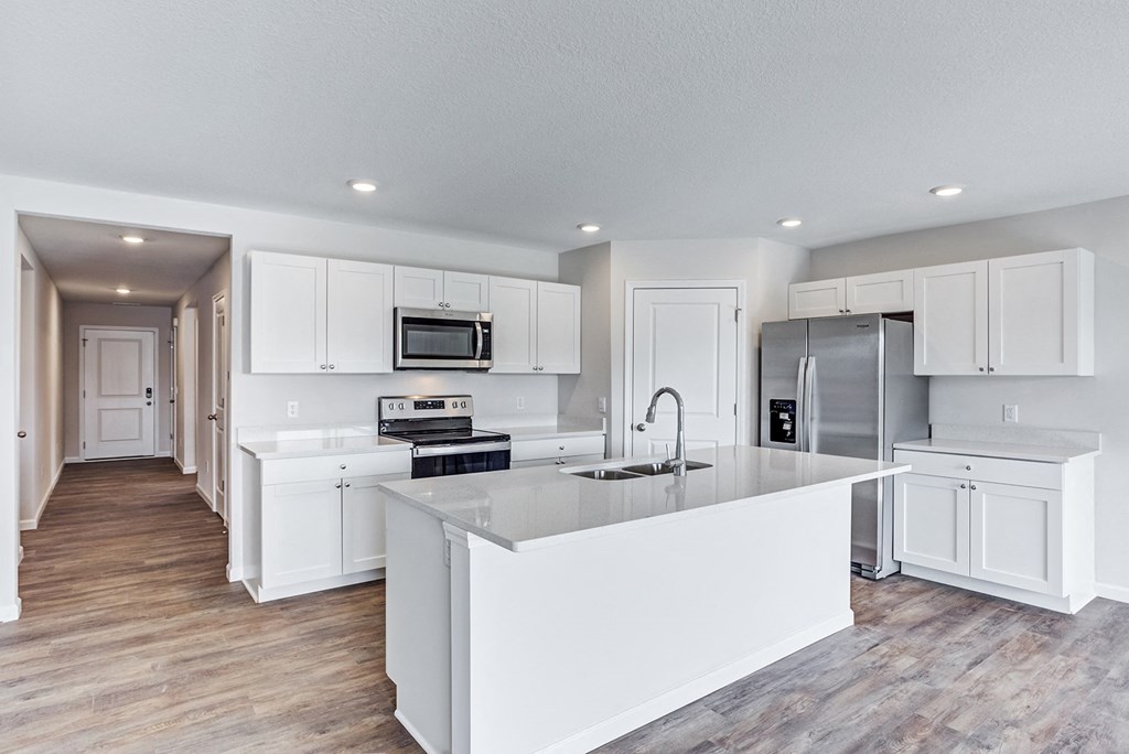 a white kitchen with a large island and stainless steel appliances