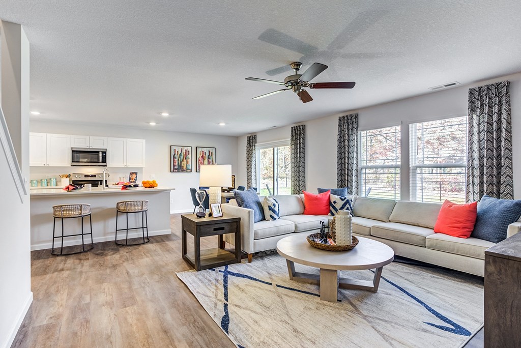 the living room and kitchen of a home with a ceiling fan