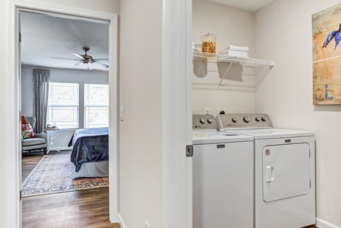 a kitchen with a washer and dryer and a bedroom with a bed