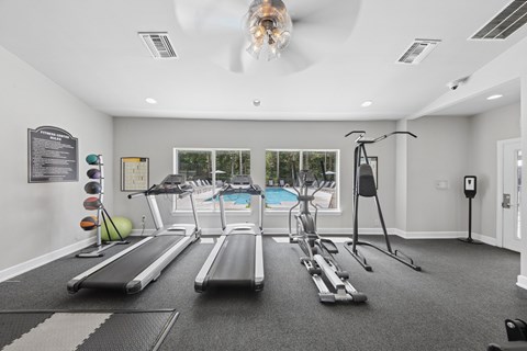 Bright resident fitness center at Lancaster Place Apartments in Calera, Alabama featuring treadmills, weight equipment, and spacious workout areas.