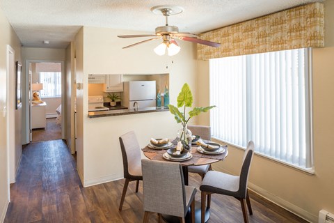A dining room with a table set for two and a ceiling fan.