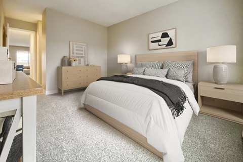 A bedroom with a large bed and a nightstand with a lamp.