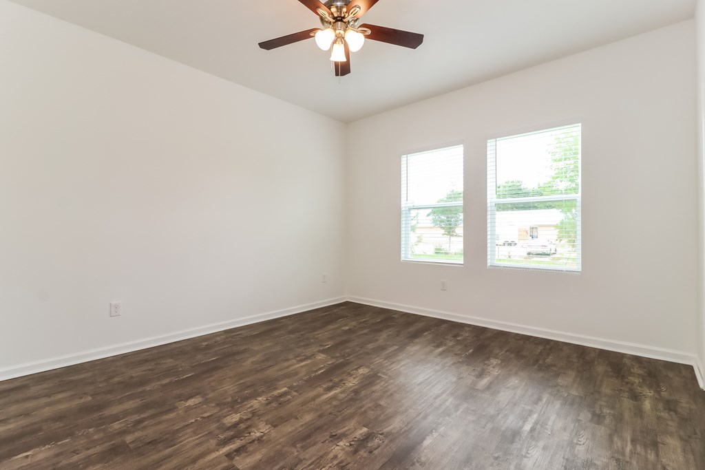 A room with a ceiling fan and wood flooring.