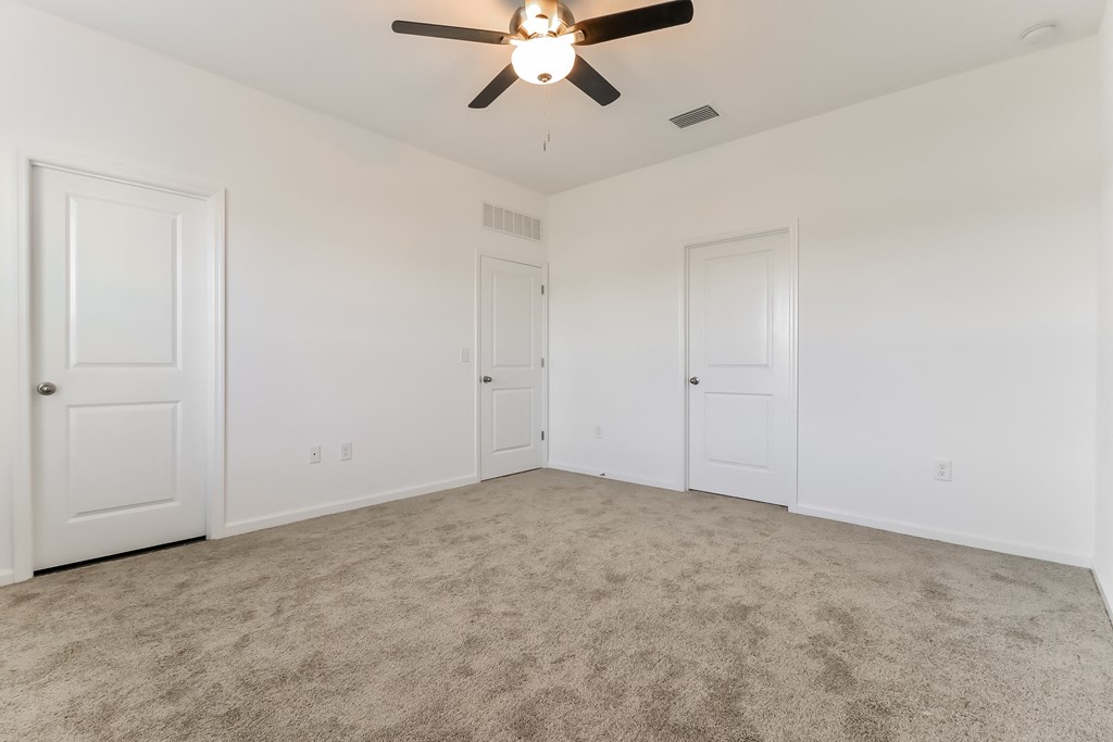 A room with a ceiling fan and carpeted floor.
