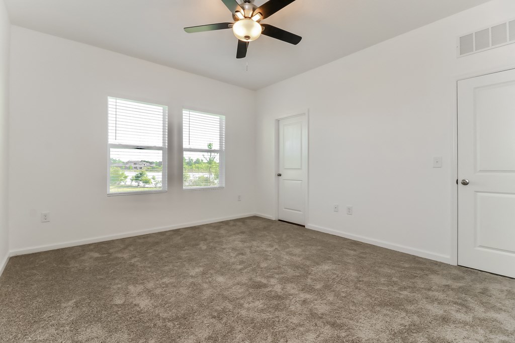 A room with a ceiling fan and carpeted floor.