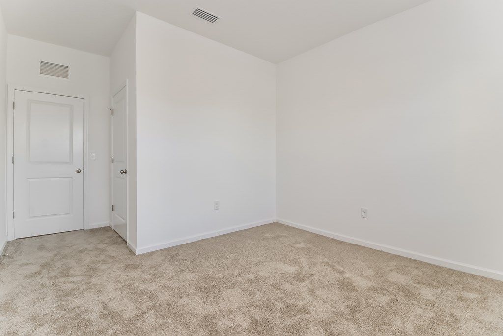 A room with a carpeted floor and two doors.