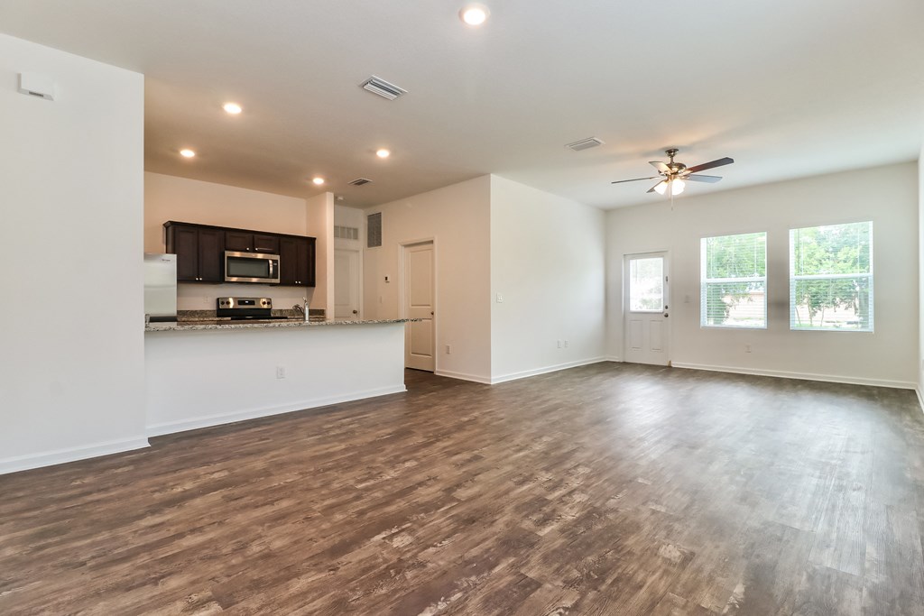 A spacious living room with a kitchen area in the background.