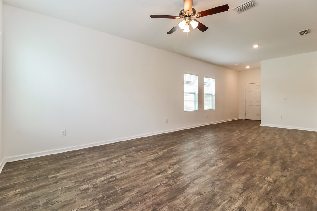 A room with a ceiling fan and wood flooring.