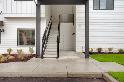 the front entrance of a white house with a staircase