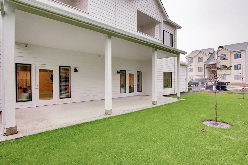 the front of a white house with a lawn and a porch