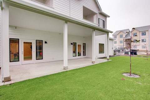 the front of a white house with a lawn and a porch