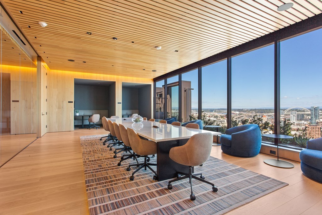 a long table with chairs sits in front of a window with a view of a city