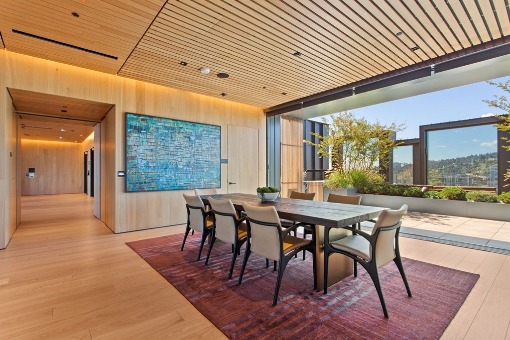 a long dining room with a wooden table and chairs and a large blue artwork on the wall