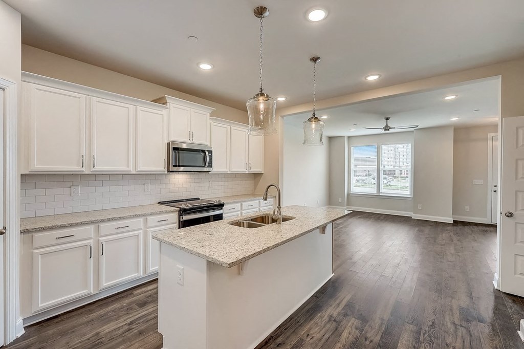 Townhomes for Rent in Gallatin, TN - The Gardens at Preston Park - Kitchen with Wood-Style Flooring, Stainless Steel Appliances, White Cabinetry, Qaurtz Countertops, and Cooking Island with Hanging Overhead Lights