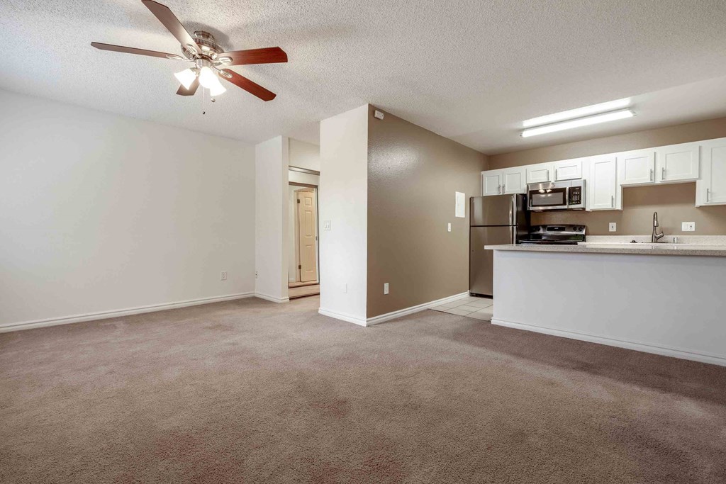 Dog Friendly Apartments in Fremont CA - Lincoln Glen - Living Room with Plush Carpet Flooring, a Ceiling Fan, and a Kitchen with Tile Flooring