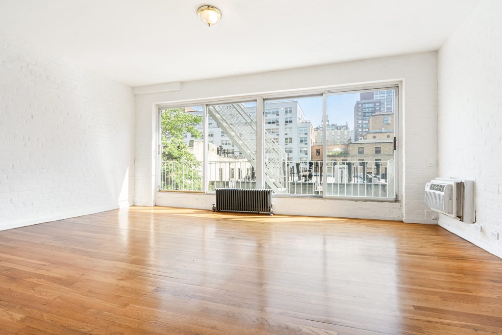 an empty living room with wood floors and a large window