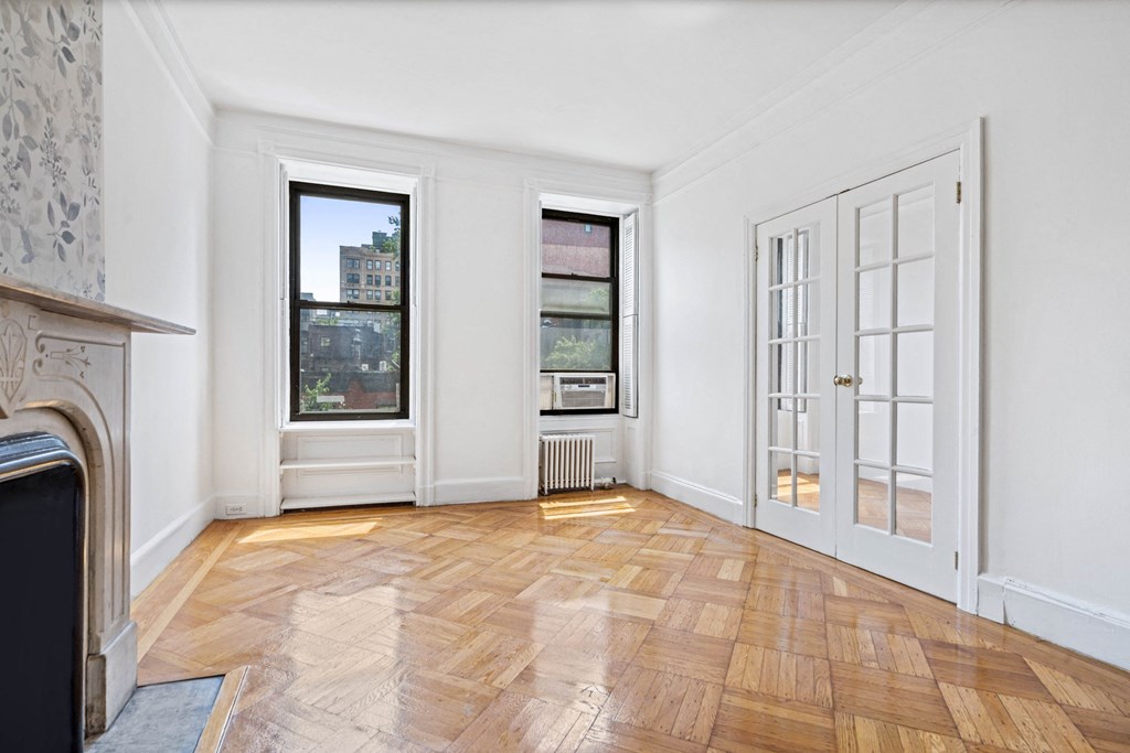 a living room with white walls and wood floors and a fireplace