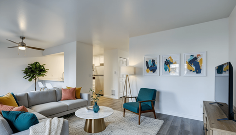 A living room with a grey sofa, a blue chair, a white coffee table, and a painting on the wall.