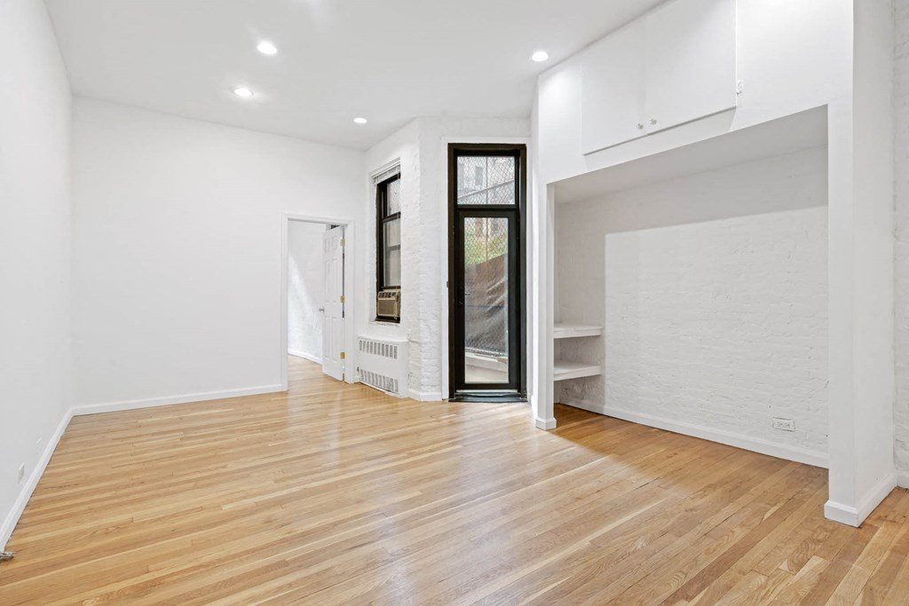 a living room with white walls and wood floors and a glass door