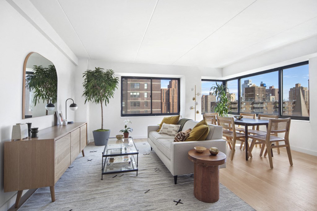 a living room with a couch and a dining table and a view of the city