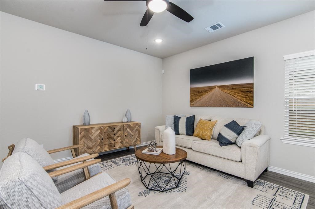 3-BR Homes for Rent in Katy, TX - Villas at Sunterra - Living Room with a Couch, Two Chairs, a Coffee Table, a Ceiling Fan, Wood-Style Flooring, a Window, and Stylish Decor