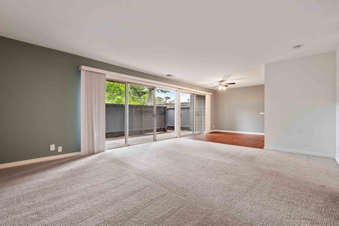 Pet-Friendly Apartments in Fremont CA - Logan Park - Spacious Open Floor Living Room with Plush Carpeting and a Dining Area with Wood-Style Flooring Leading to the Private Patio