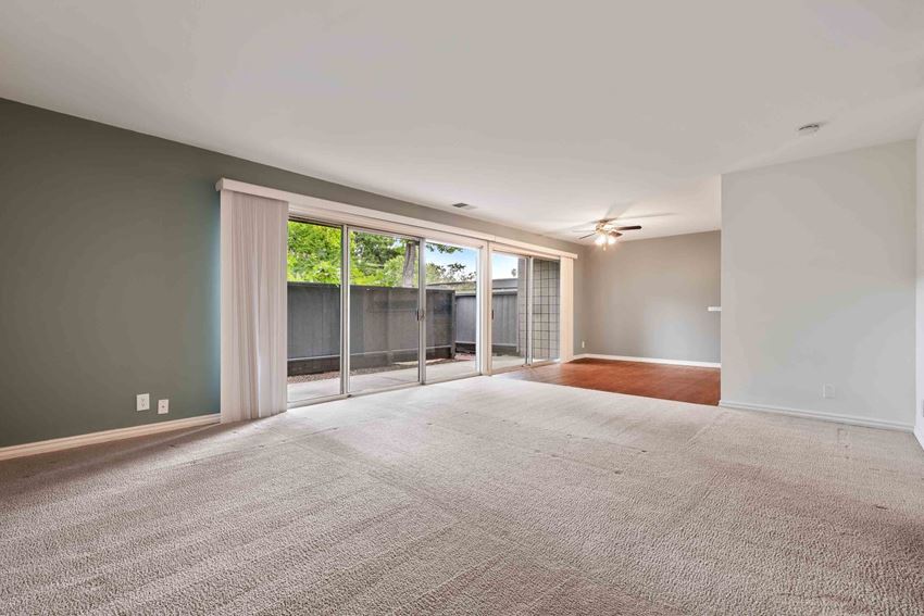Pet-Friendly Apartments in Fremont CA - Logan Park - Spacious Open Floor Living Room with Plush Carpeting and a Dining Area with Wood-Style Flooring Leading to the Private Patio