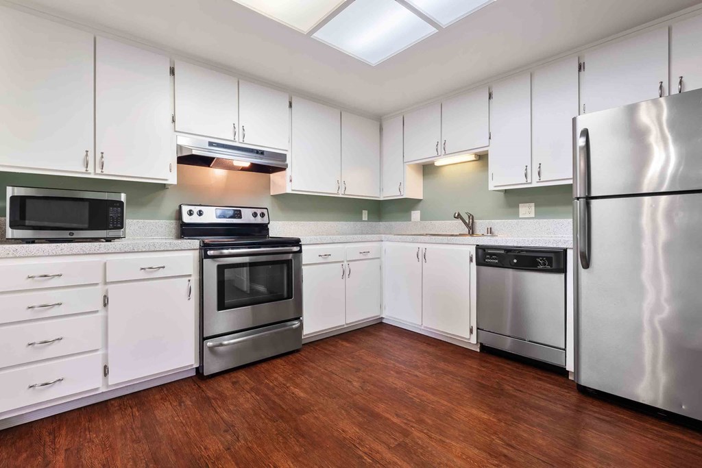 Apartments for Rent in Fremont CA - Logan Park - Spacious Kitchen with Wood-Style Flooring, Speckled Grey Countertops, White Cabinets, and Stainless Steel Appliances