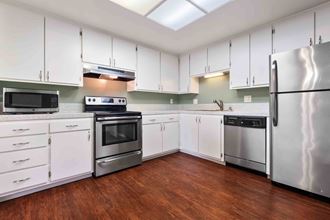 Apartments for Rent in Fremont CA - Logan Park - Kitchen with Stainless Appliances, White Cabinets, and Wood-Style Flooring