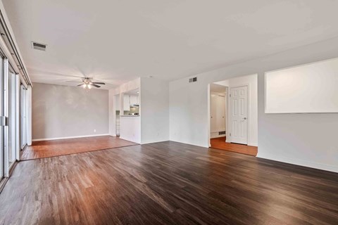 Fremont, CA, Apartments - Logan Park - Living Room with Wood-Style Flooring, Access to the Dining Room, Ceiling Fan, and Sliding Glass Doors to a Patio.