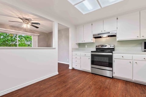 a kitchen with white cabinets and a stove and a ceiling fan
