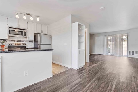 an open kitchen and living room with a counter top and a refrigerator