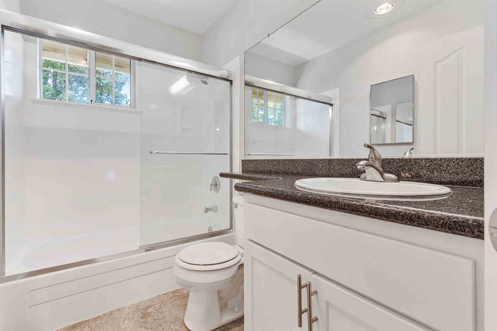 One Bedroom Apartments in San Jose CA - Los Gatos Creek - Bathroom with Small Window, Dark Countertops, and White Cabinetry
