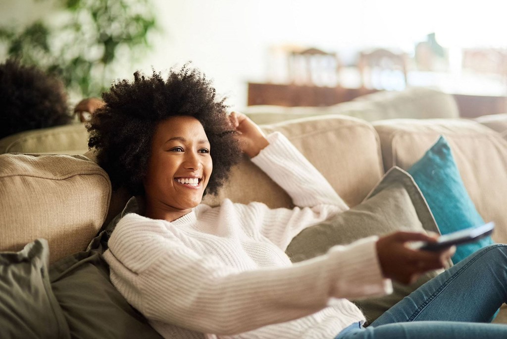 a woman laying on a couch with a remote control