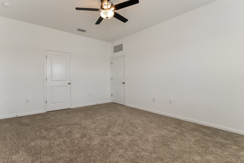 A room with a ceiling fan and carpeted floor.