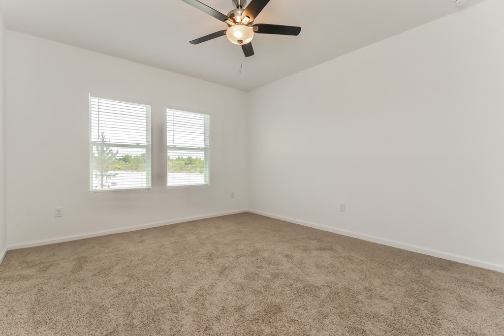 A room with a ceiling fan and carpeted floor.