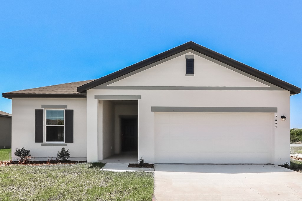 A white house with a black roof and a garage door.