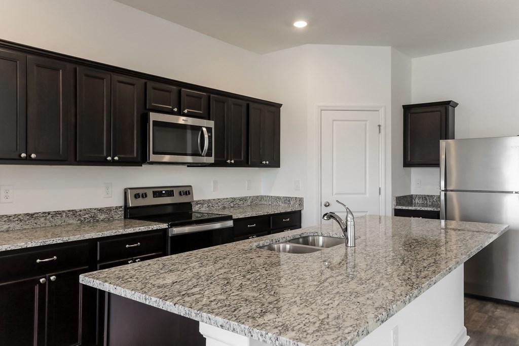 A kitchen with granite countertops and stainless steel appliances.