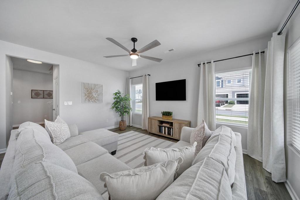A living room with a grey sofa and a ceiling fan.