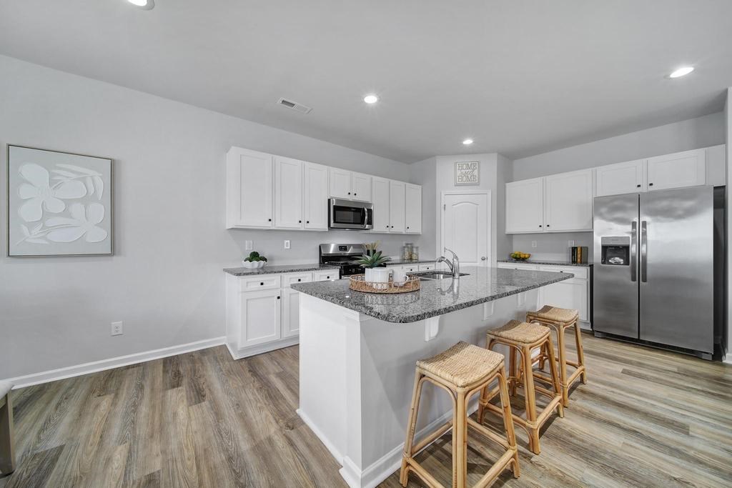 A kitchen with white cabinets and a wooden floor.
