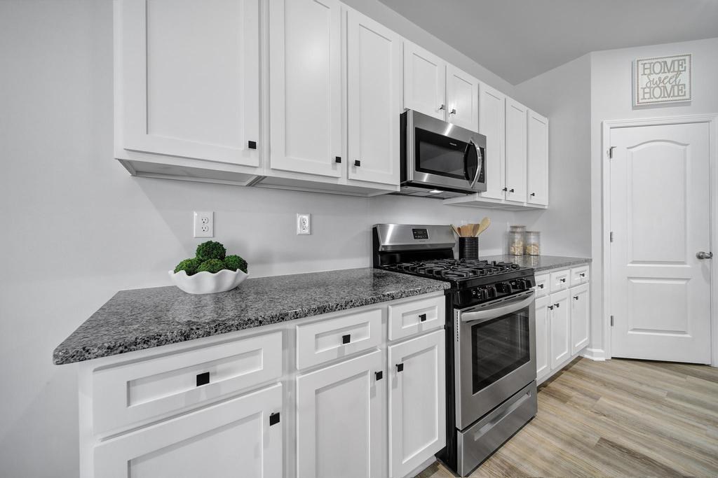 A kitchen with white cabinets and a granite countertop.