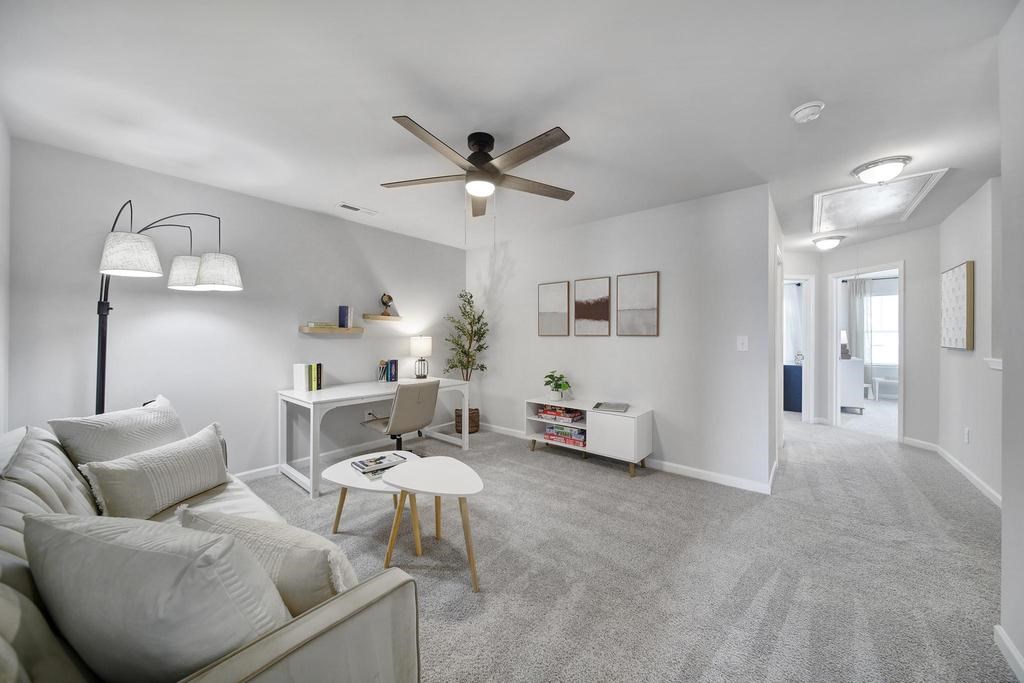 A living room with a grey carpet and a white couch.