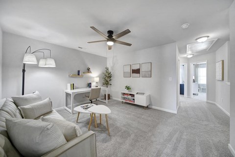 A living room with a grey carpet and a white couch.