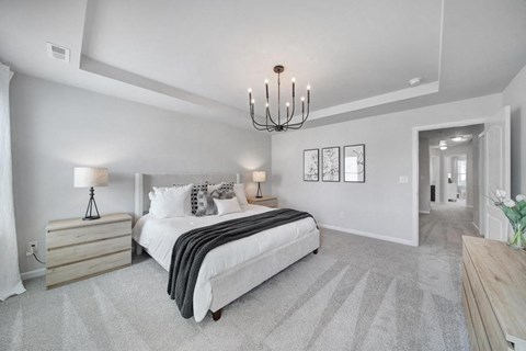 Spacious bedroom with large bed and chandelier in pet-friendly townhome in Indian Trail, NC