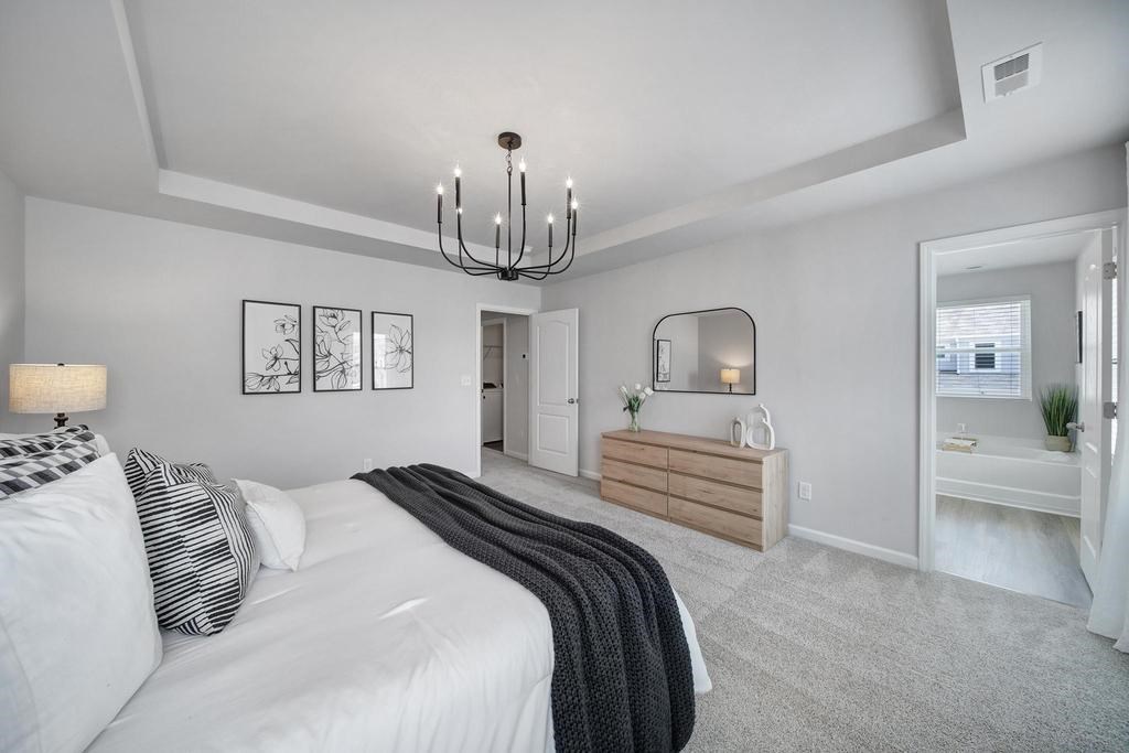 A bedroom with a large bed and a chandelier.