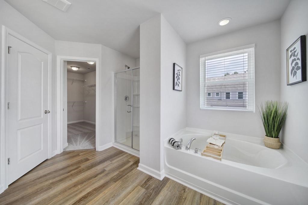 A white bathroom with a large tub and a window.